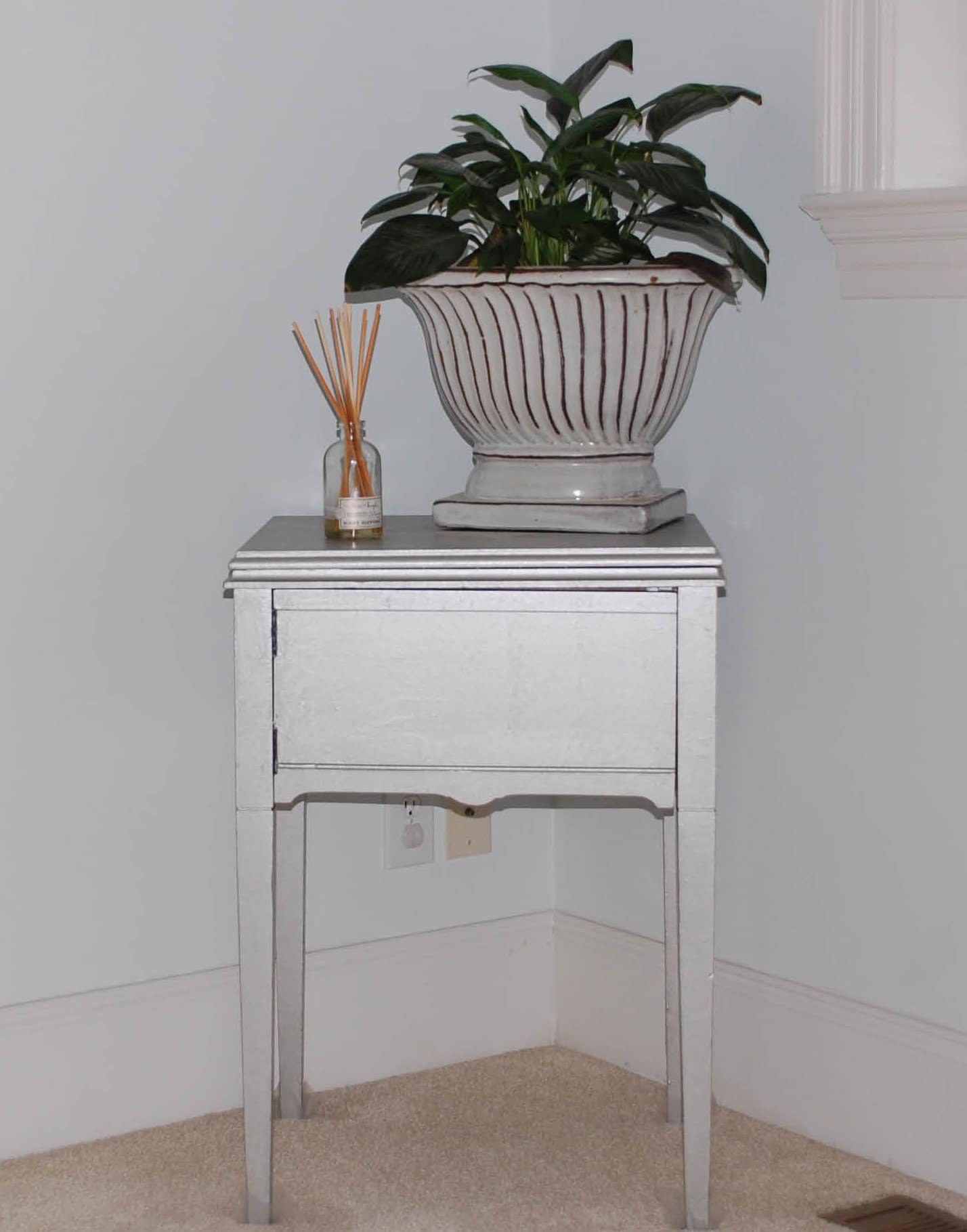 wood sewing cabinet after painting sitting in our bedroom with potted plant on top