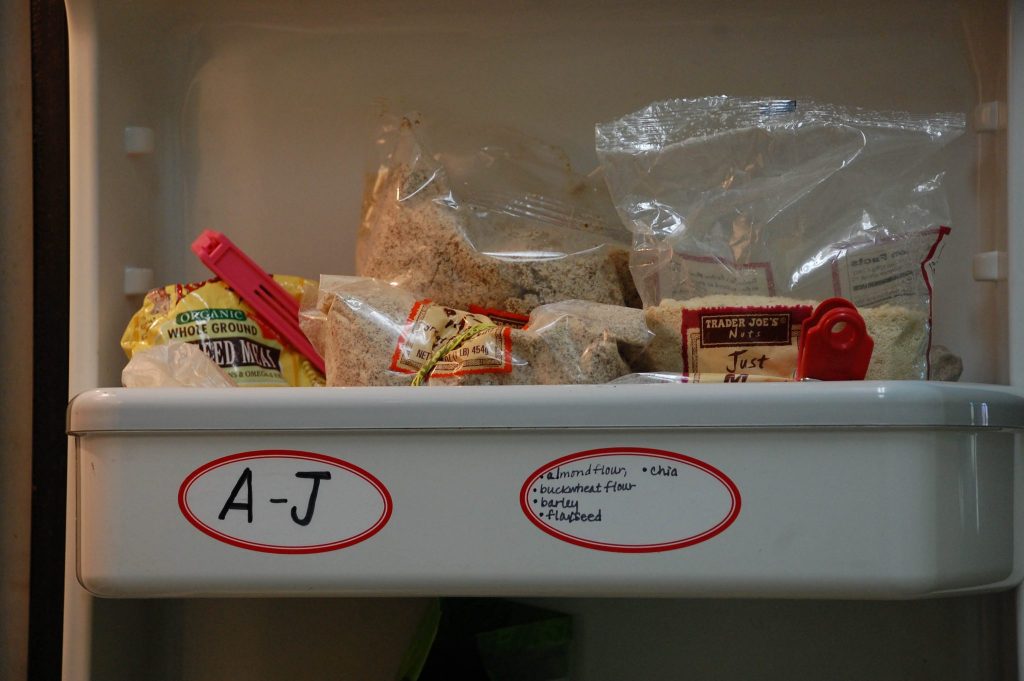 Close up of shelf in spare refrigerator labeled alphabetically with contents to help keep pantry organized 