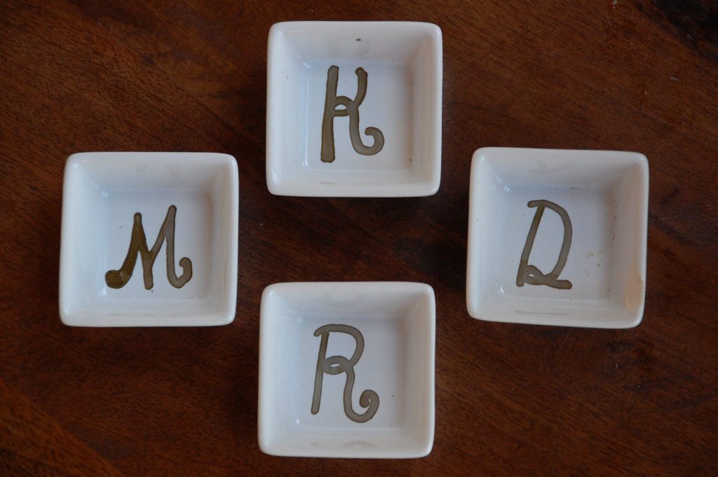 small bowls, empty with initials written on the bottom placed side by side on the table