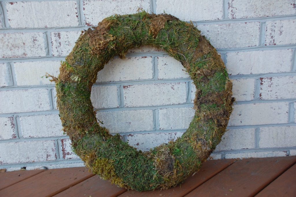 Outdoor Spring supplies: unadorned moss wreath on porch before decorating