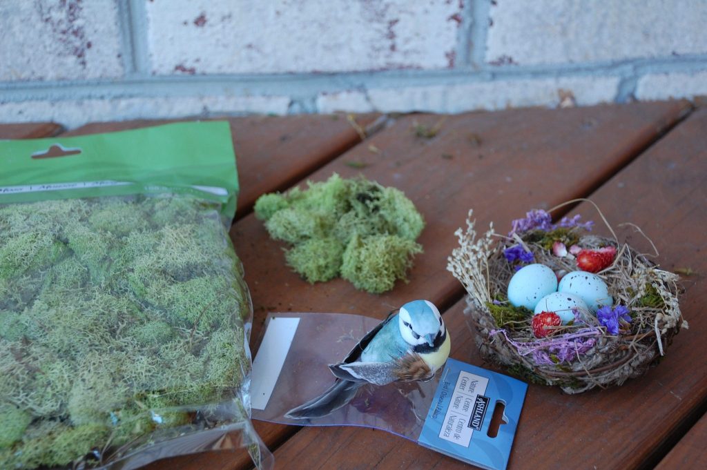 DIY Spring Wreath Supplies: close up of moss wreath supplies, moss, bird nest with eggs, and small plastic toy bird 