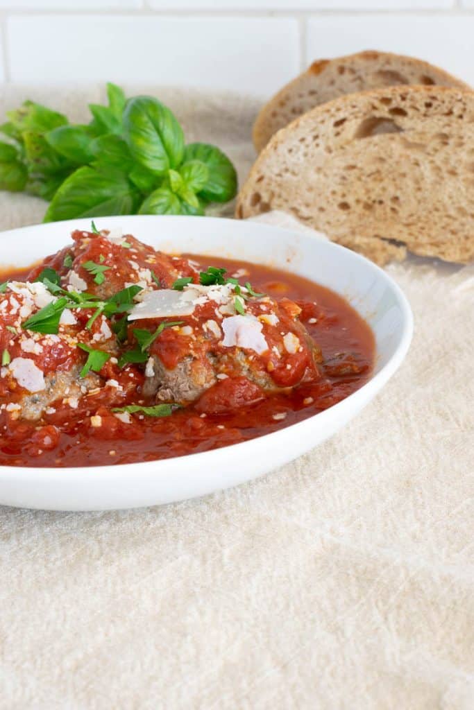 Three meatballs in sauce in a bowl.