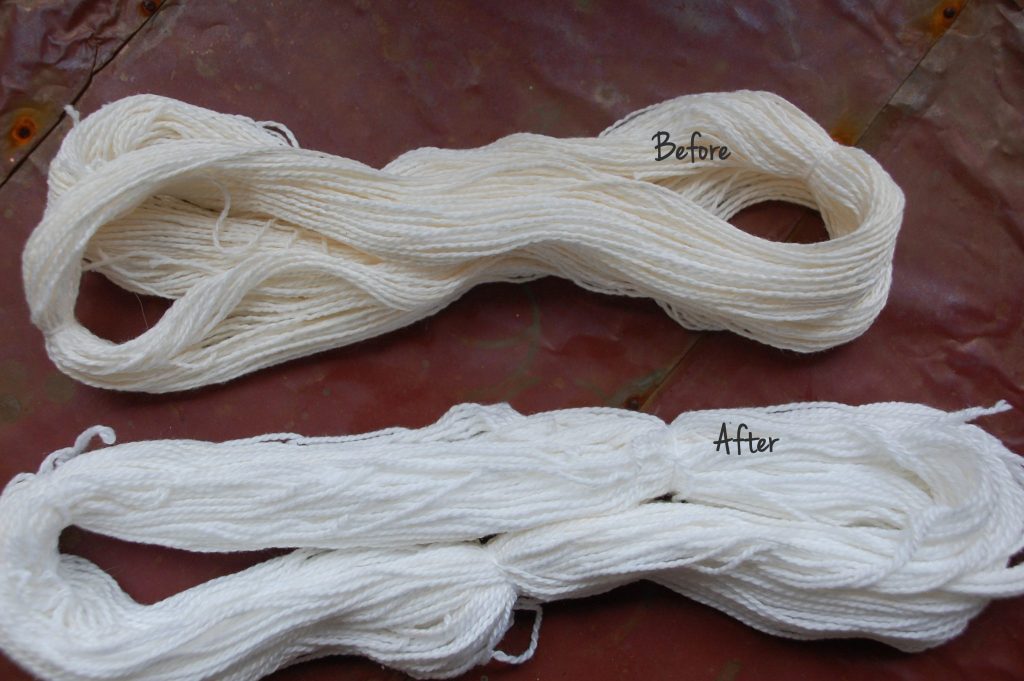close up comparing white yarn laying on table before and after washing. Yarn after washing is visibly cleaner and brighter color
