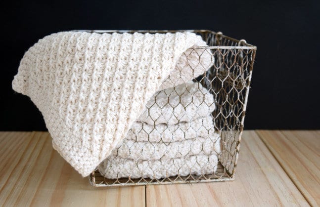 White hand-knit washcloths in a wire basket.
