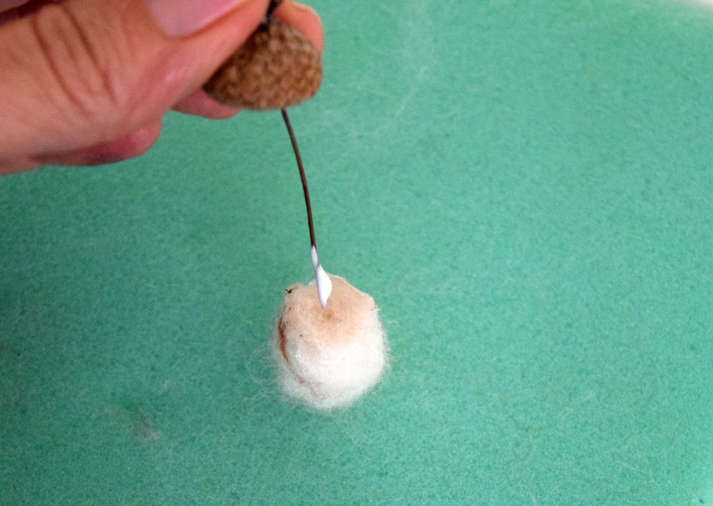 Wire going into acorn. Illustrated Instructions to make needle felted acorns and needle felted acorn napkin rings. Perfect for your Fall and Thanksgiving table.