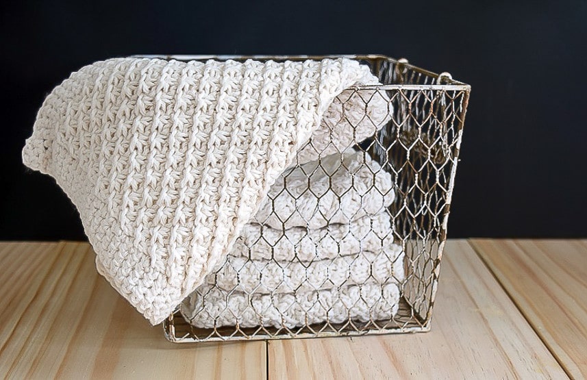 Beige washcloths in a wire mesh basket.