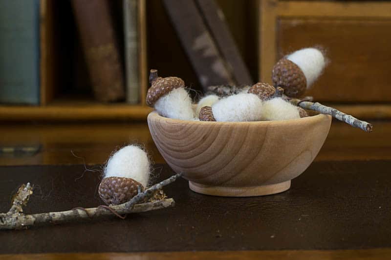 Wooden bowl filled with needle felted acorns.