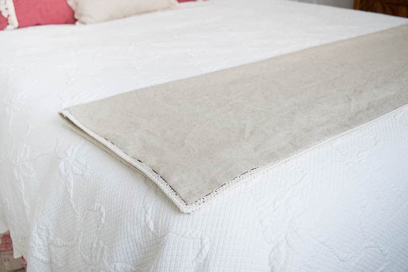 A beige linen throw on a white bed.