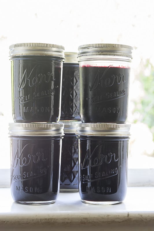 Jars of jam in front of a window.