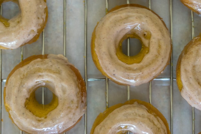 Baked Pumpkin Donut Recipe: Baked donuts cooling on tray covered in chai glazeai 