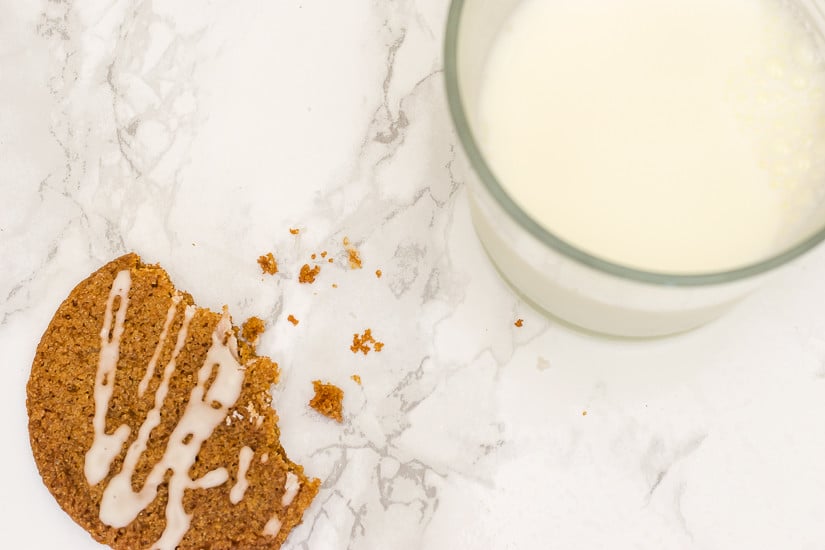 Glazed Ginger Molasses Cookie Recipe: half-eaten glazed cookie next to a glass of milk