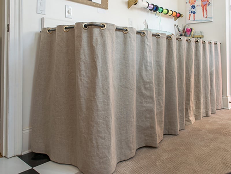 Step by step instructions and material needed to make a grommeted counter skirt. This DIY skirted counter not only finishes my room decor, but it also does a great job hiding storage.