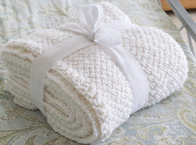 Basket Weave Blanket Pattern: Finished knit blanket folded, wrapped in a bow on the bed ready for gifting