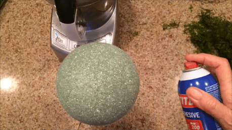 spraying adhesive to the foam ball