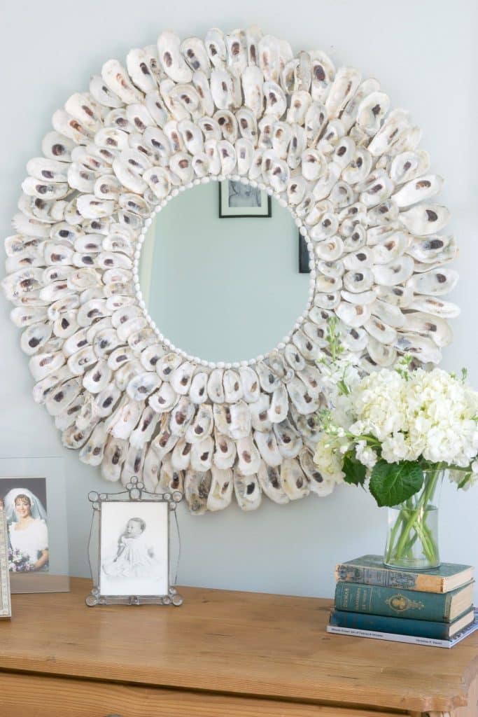 Oyster shell mirror with vase of flowers