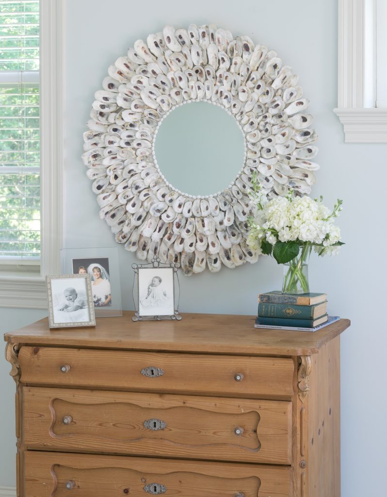 Oyster shell mirror against a pale blue wall.