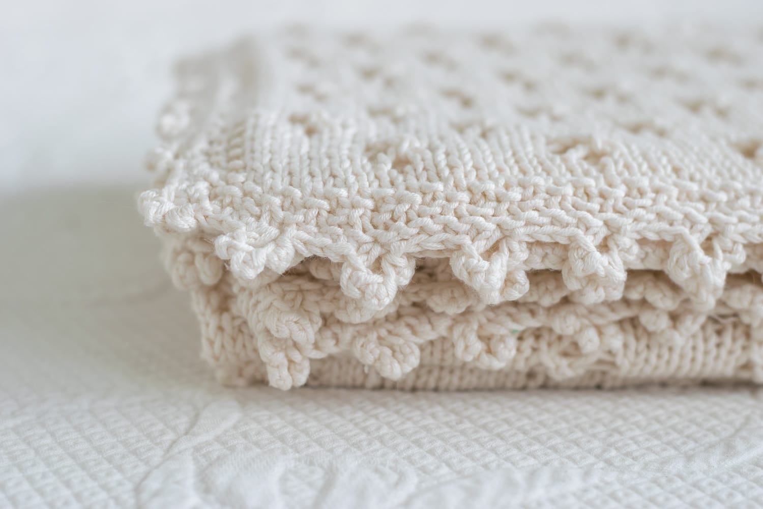 Close up of cloverleaf crochet edge on knit baby blanket