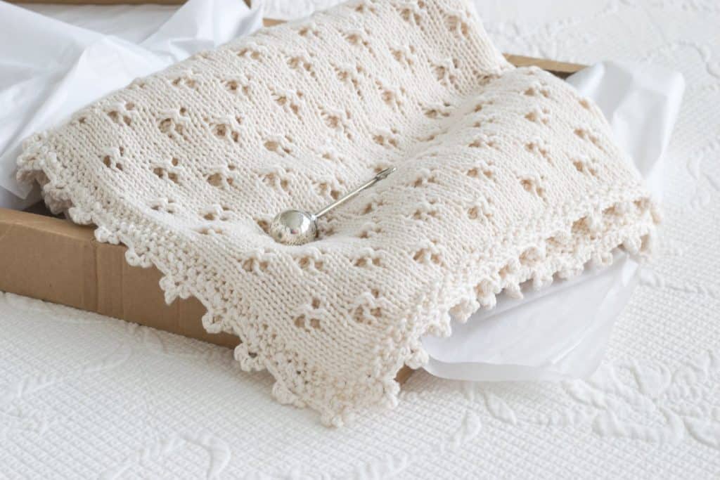 Knit Eyelet Baby Blanket in a gift box with a silver rattle.