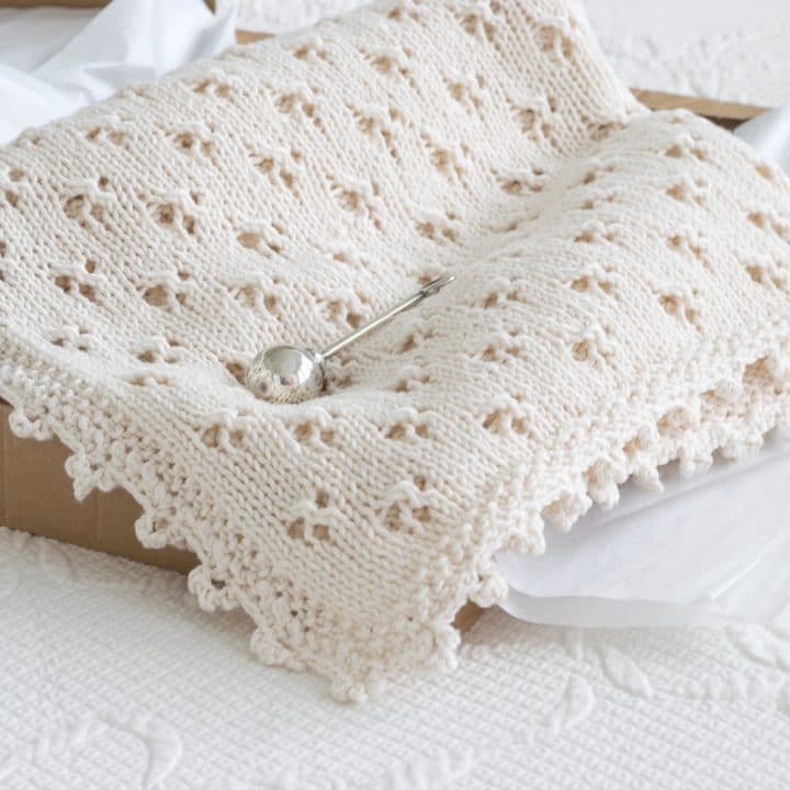Knit Eyelet Baby Blanket in a gift box with a silver rattle.