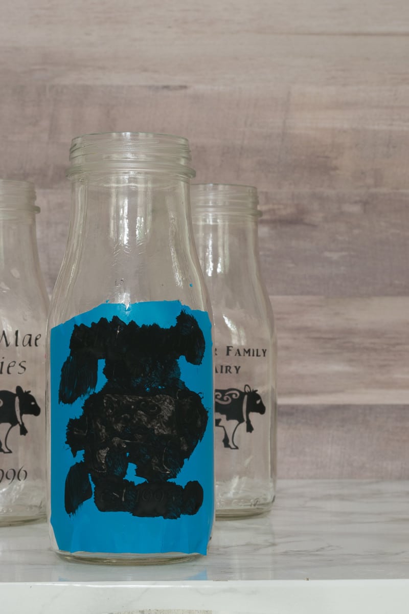 Three thin layers of paint make sure that the paint doesn't seep under the stencil on the DIY glass milk bottle