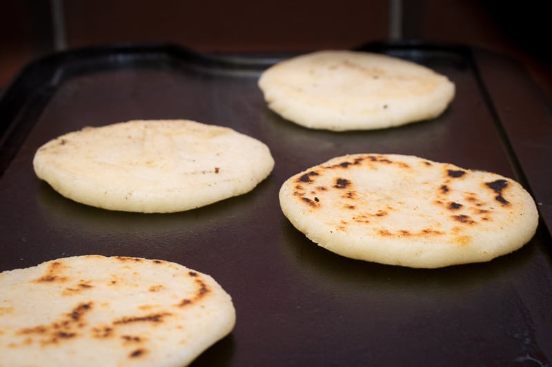 Easy Arepas Recipe: Arepas cooking on griddle