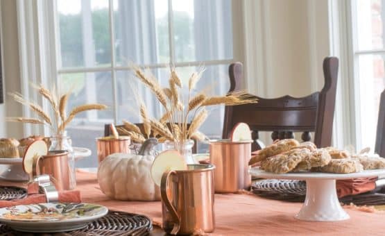 Copper mugs and fall grass on a table.