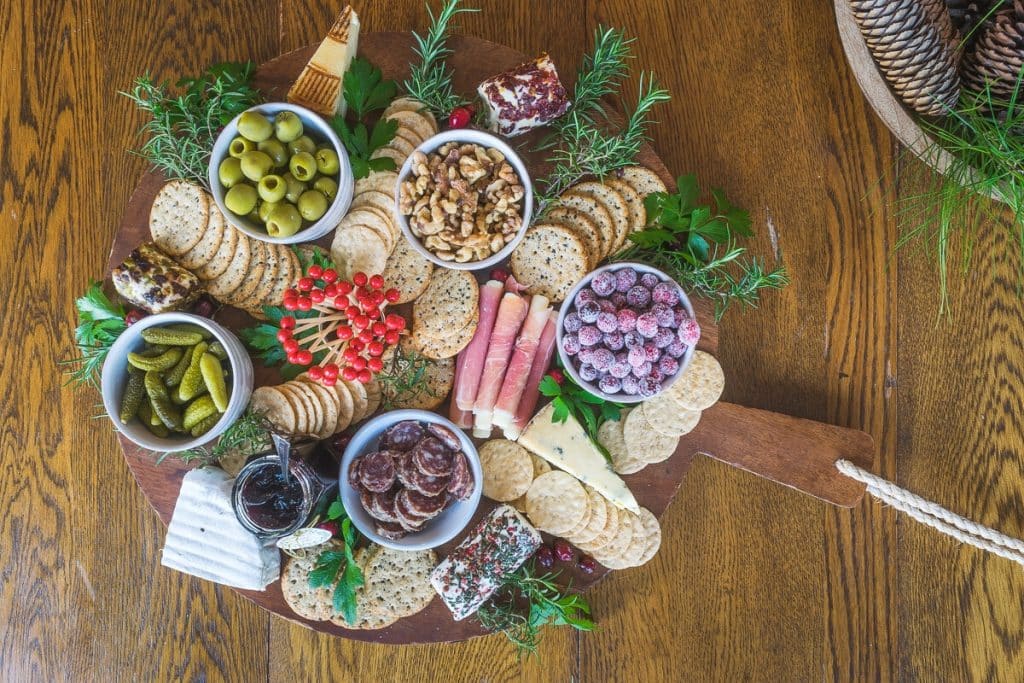 Charcuterie Board with crackers, cheese, meat, nuts, olives and sugared cranberries.