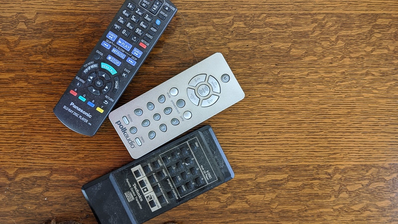Remote controls sitting on top of a wooden table.
