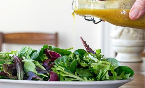 Pouring Curry Salad Dressing over Salad Greens