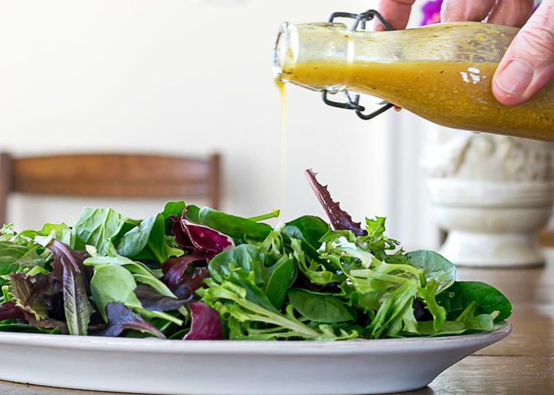 Pouring Curry Salad Dressing over Salad Greens