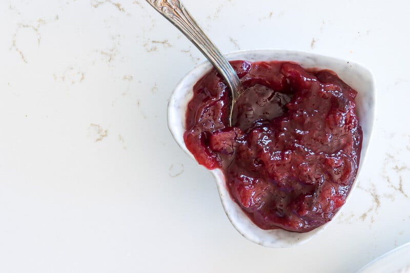 heart shaped bowl with plum jam and spoon.