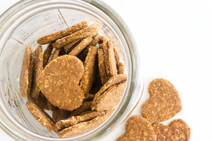 Heart-shaped dog treats in a jar and on a counter.