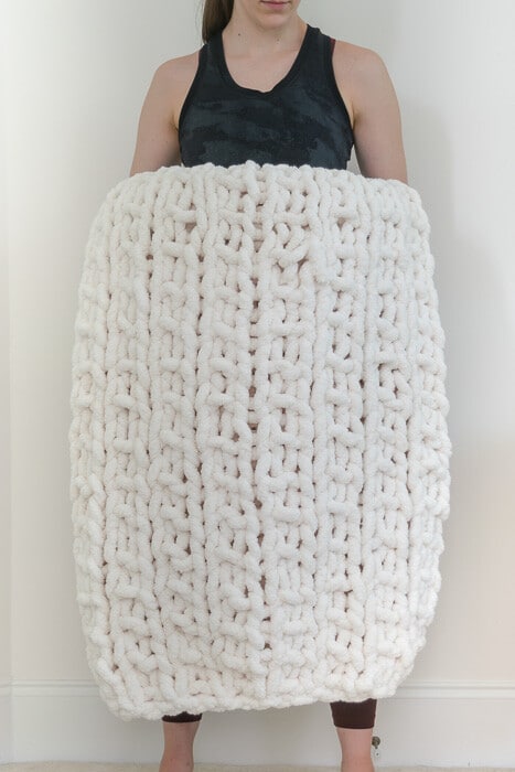 Girl holding large chunky knit blanket