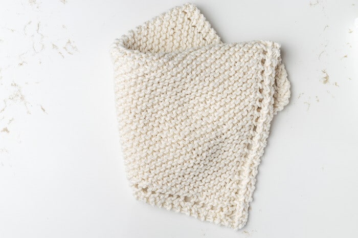 A partially folded beige knit washlcoth.