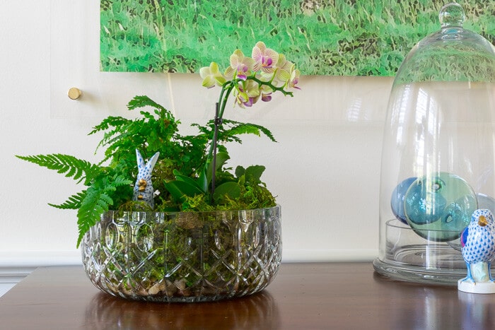 A crystal bowl with orchids and ferns.