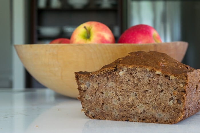 Apple spice bread with a bowl of apples in the background.