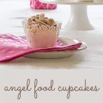 Angel Food Cupcake on a pink napkin with several cupcakes on a cake stand in the background.