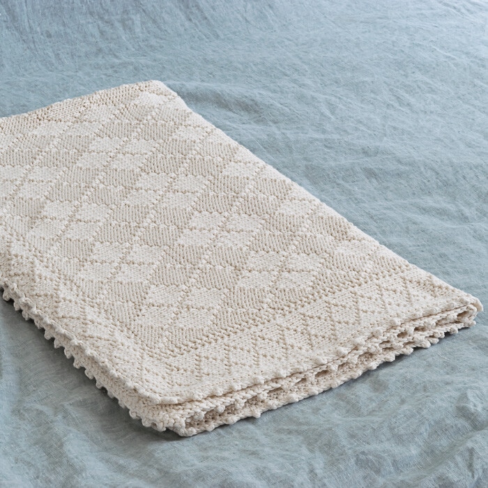 White argyle knit baby blanket on blue blanket.