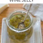Jar of Jalapeno Wine Jelly on a square plate with a small spoon.