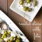 Roasted olives on a small square plate with larger platter on the side.