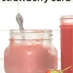 Jar of Strawberry Curd with a spoon in the jar and strawberry in front of the jar.