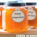 Jar of Orange Marmalade on a wooden board, with several other jars in the background..
