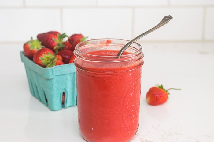 Strawberry puree in a jar with a spoon.