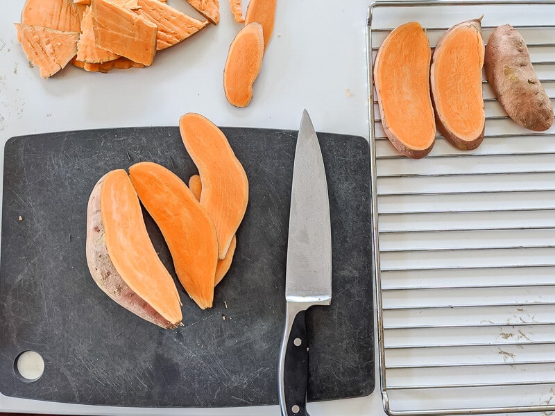 How to make sweet potato dog chews: Sliced Sweet Potatoes on cutting board and on rack before going in oven.