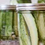 A closeup of a jar of refrigerator dill pickles, with other jars in the background.