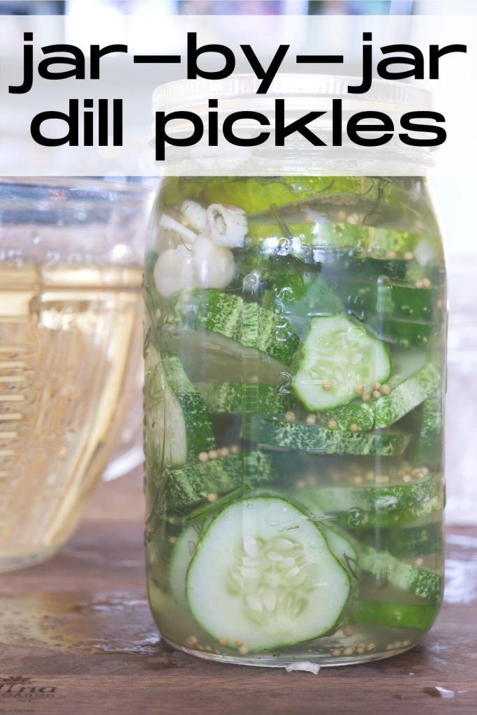 jar of dill pickles, with a container of pickle brine in the background.