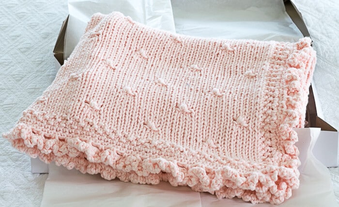 Pink Knit Baby Blanket with a crochet ruffle edge in a gift box.