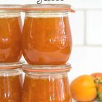 Jars of Apricot Jam with apricots in the background.