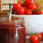 jar of tomato jam with a bowl of tomatoes in the background.