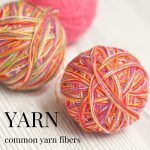 Three balls of yarn in shades of pink and orange on a white background.